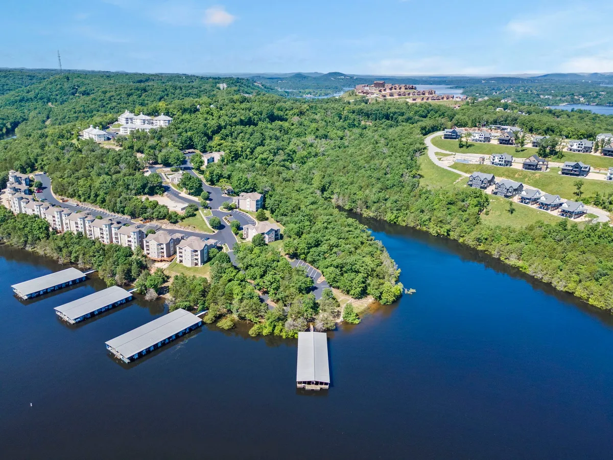 An expansive waterfront scene featuring marinas, residential buildings, and lush greenery. The landscape is serene, with calm waters reflecting the sky and a sense of welcoming community along the shoreline.