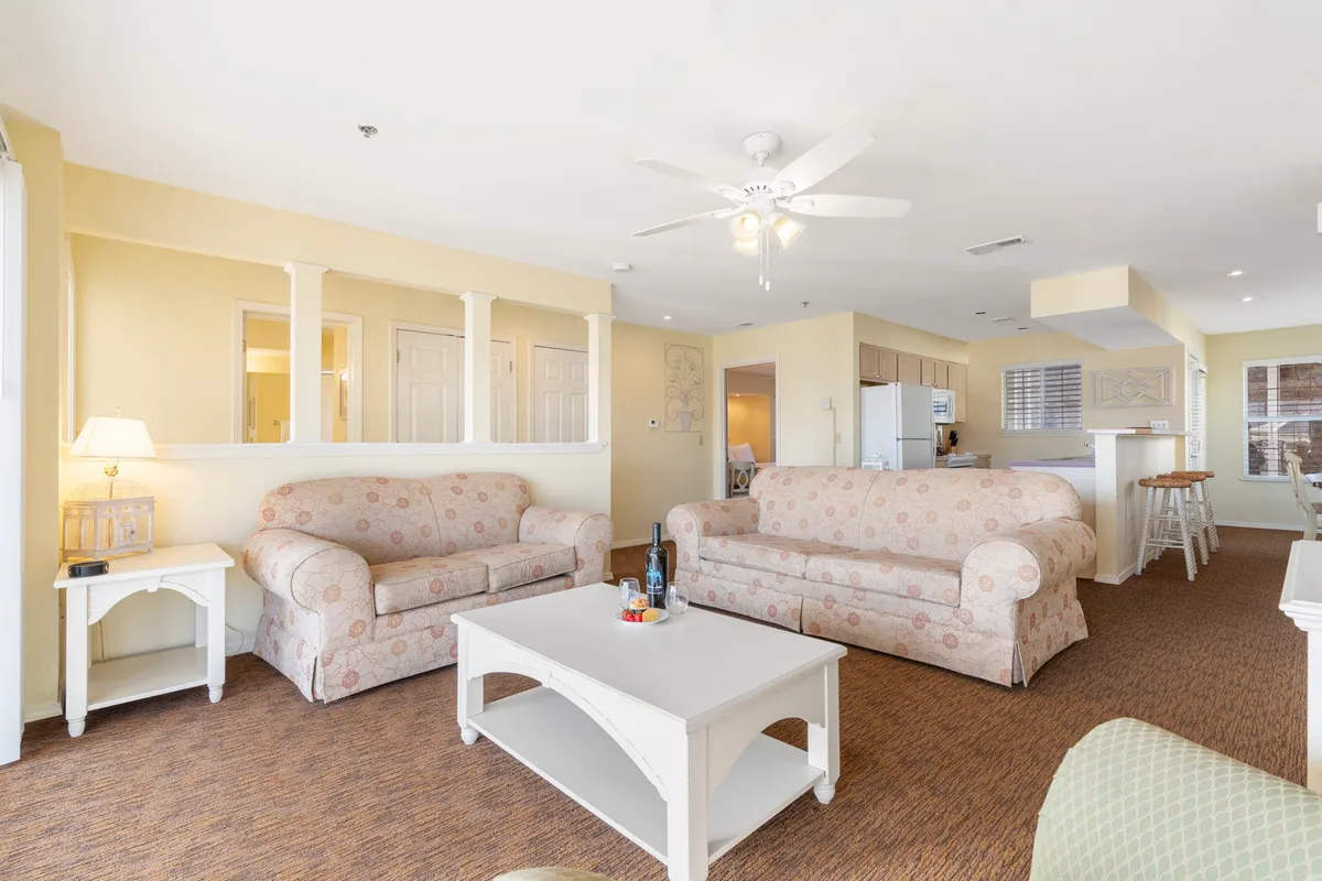 A wide view of the living space reveals comfortable sofas, a central coffee table, and an adjoining kitchen area. The layout is ideal for gathering, socializing, and enjoying game nights or movie marathons, consistent with the section's narrative.