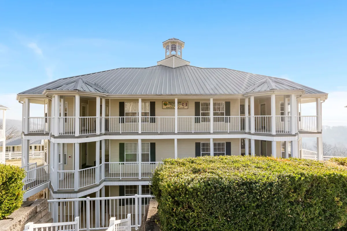 The distinctive round architecture of the resort building is surrounded by manicured greenery. The decorative roof with a cupola and inviting balcony showcase the property’s unique style and connection to outdoor living.