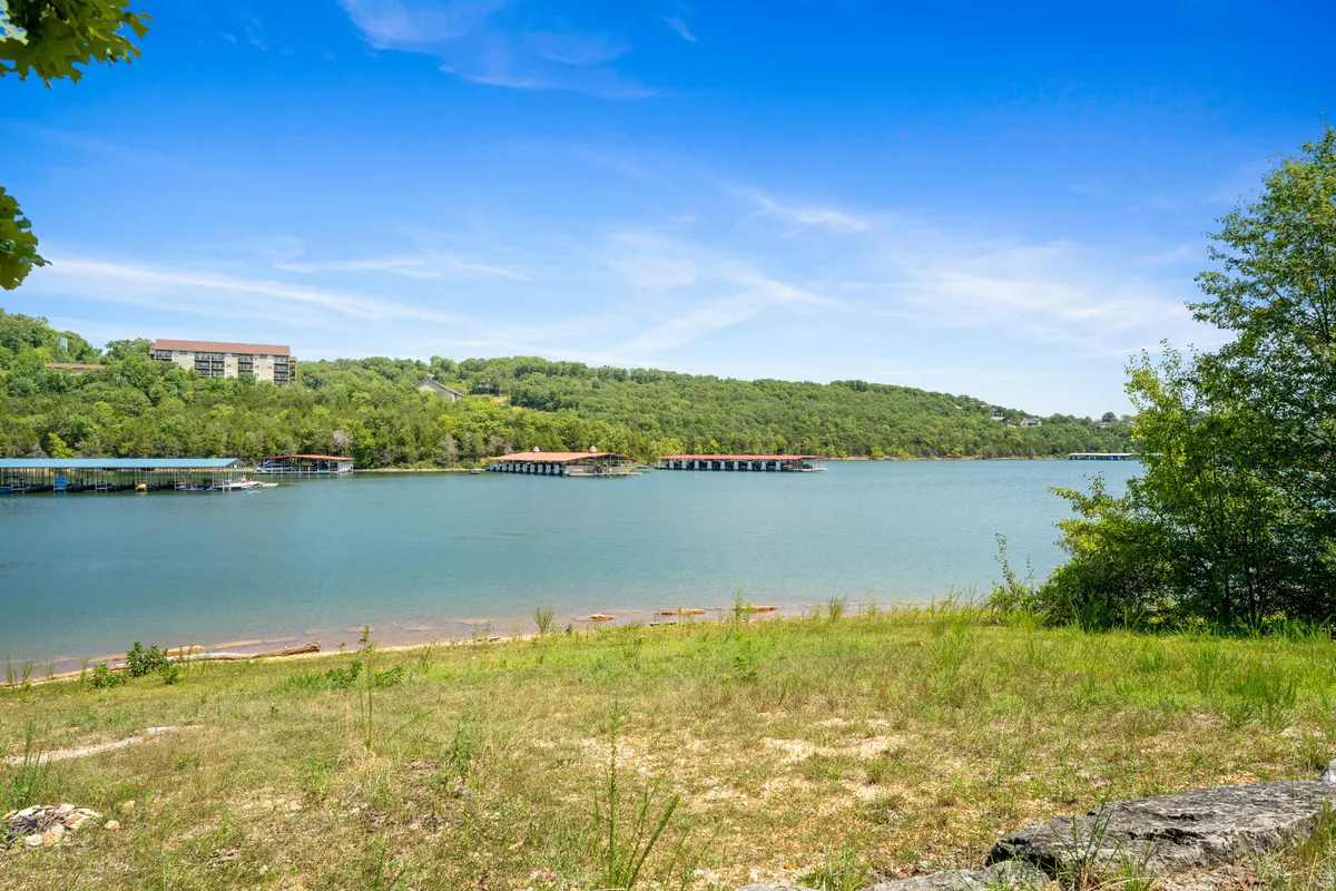 A tranquil, panoramic view of Table Rock Lake with calm water, distant green hills, and a few boathouses along the shoreline. The image evokes a sense of peace and natural beauty, perfect for anyone seeking a serene lakeside escape.