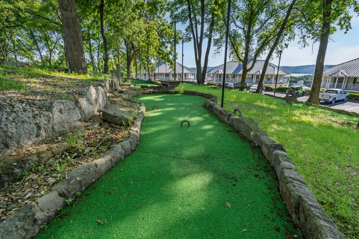 A vibrant mini-golf course nestled among lush greenery with a defined pathway. The scene suggests friendly competition and fun outdoor activities, perfect for group play.