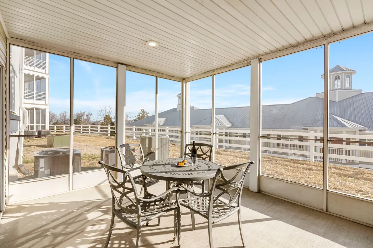 The image shows a cozy dining area with a table topped with decorative fruit, surrounded by windows that fill the space with warm morning sunlight. Through the windows, there's a beautiful view of the outdoors, suggesting proximity to Table Rock Lake and the natural beauty of the Ozarks. The atmosphere is inviting, ideal for sharing meals, sipping coffee, and enjoying quality time together.