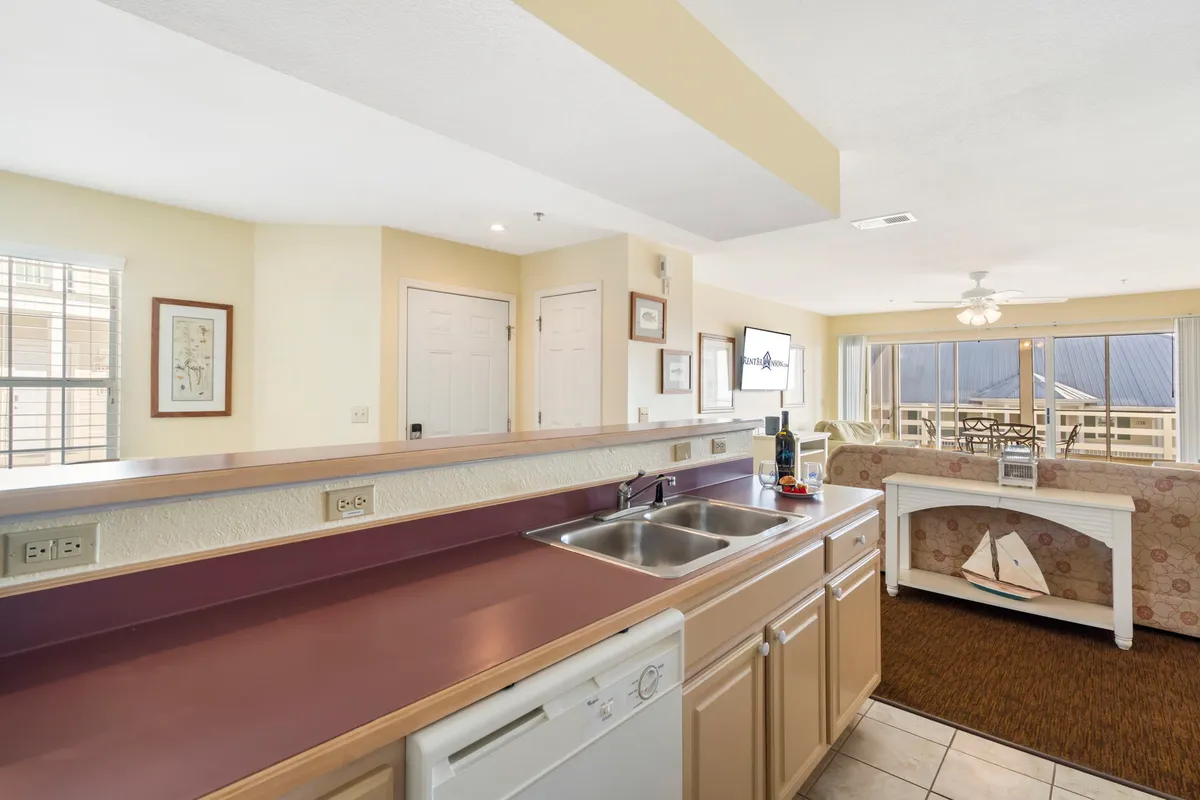 A spacious, well-lit kitchen with ample countertops and a modern sink. The open layout leads smoothly into the adjacent dining area, and large windows offer a scenic view, enhancing the sense of warmth and sociability. The space is clearly designed for both cooking and entertaining, suggesting lively family gatherings or quiet mornings with coffee.